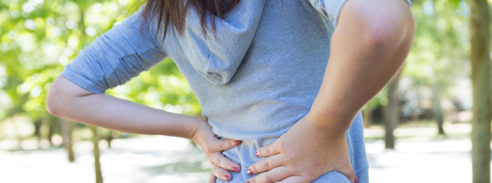 Female holding her lower back in discomfort.